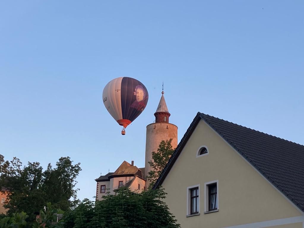 Ein Heißluftballon schwebt vor der Burg Posterstein